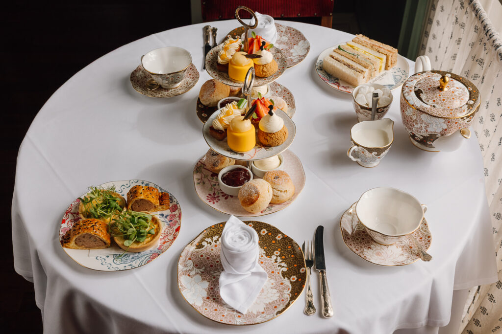 A selection of sandwiches and sweet treats on fine china, with tea.