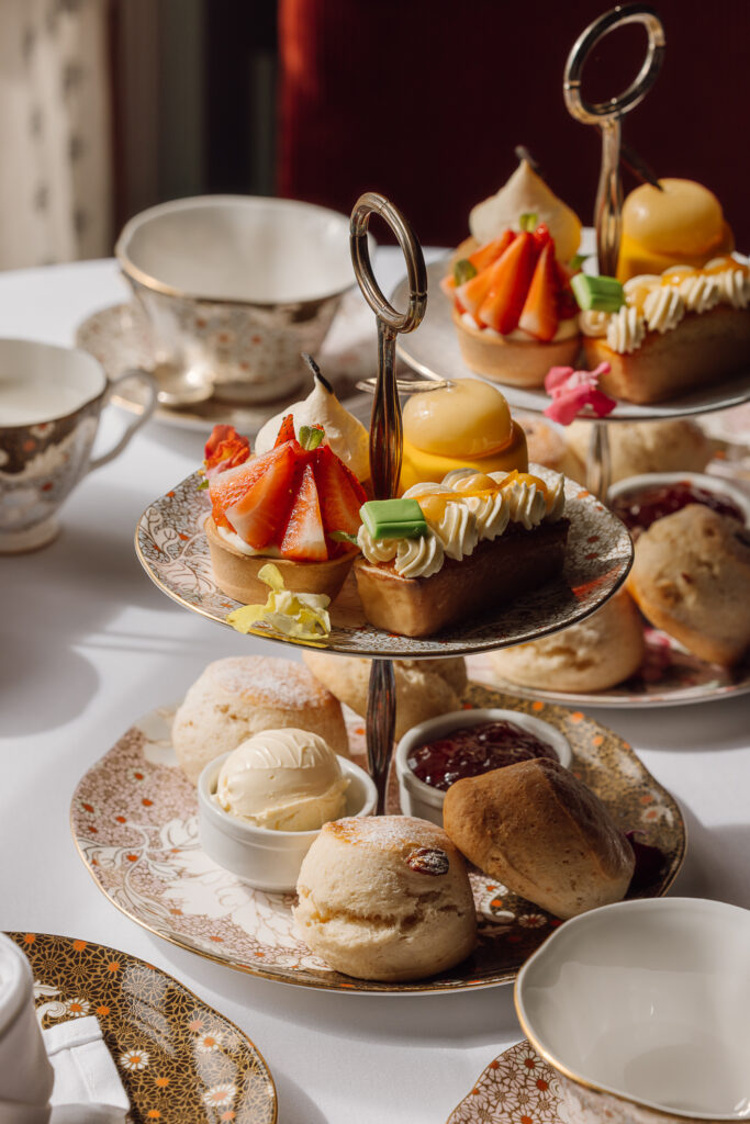 A selection of sandwiches and sweet treats on fine china, with tea.